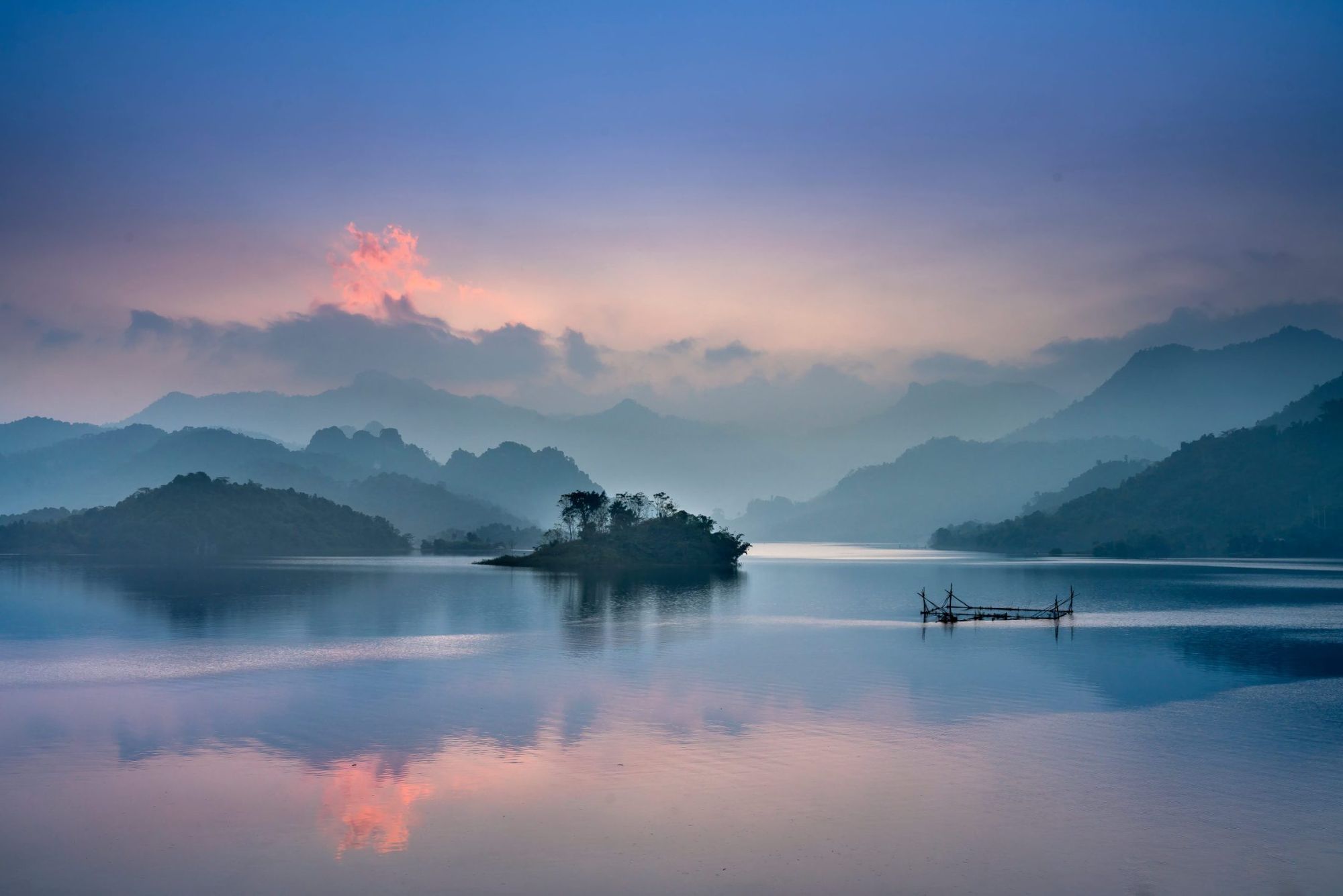 Lac au coucher du soleil, montagnes dans la brume